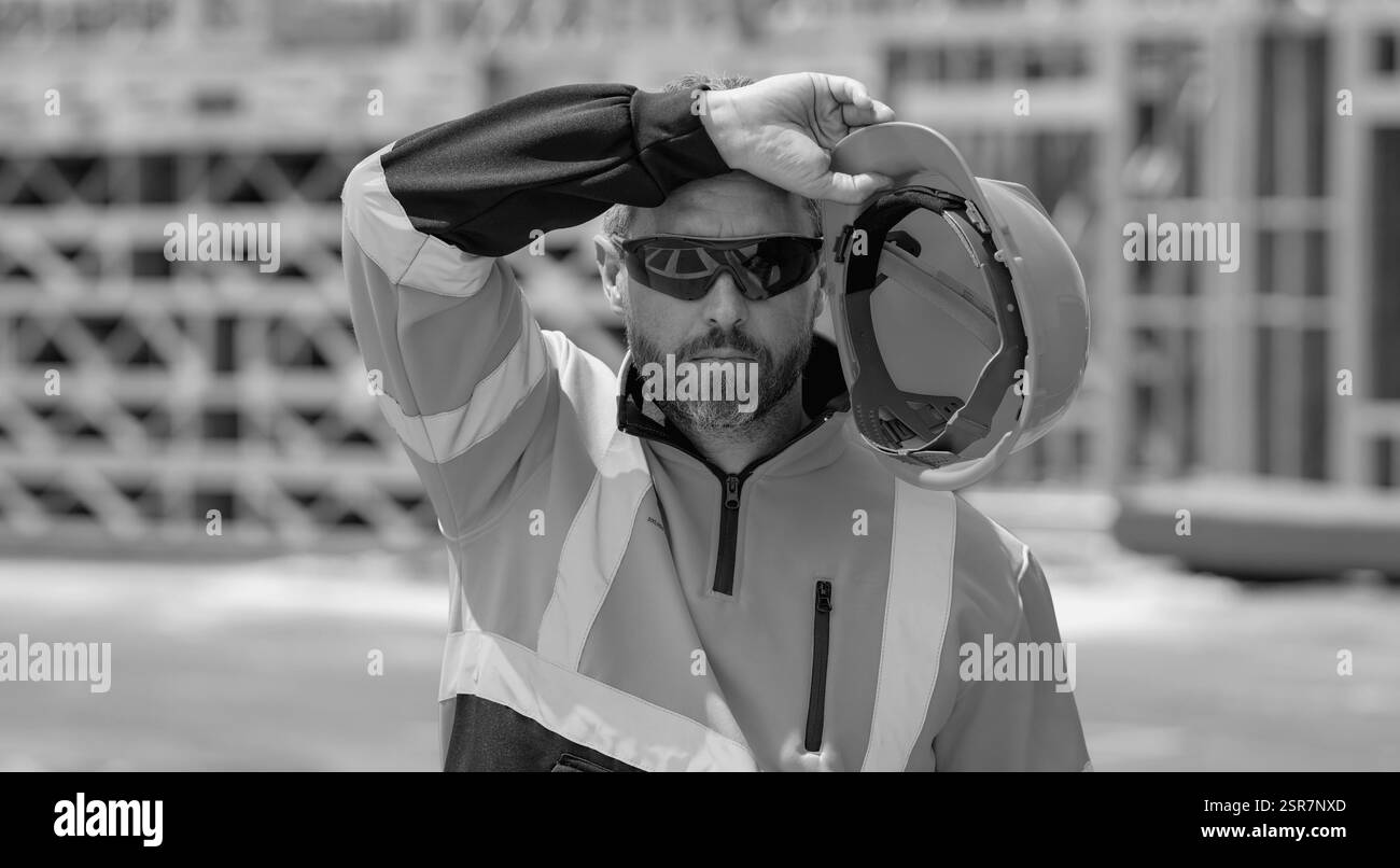 Tired, overworked worker in building uniform on buildings construction ...