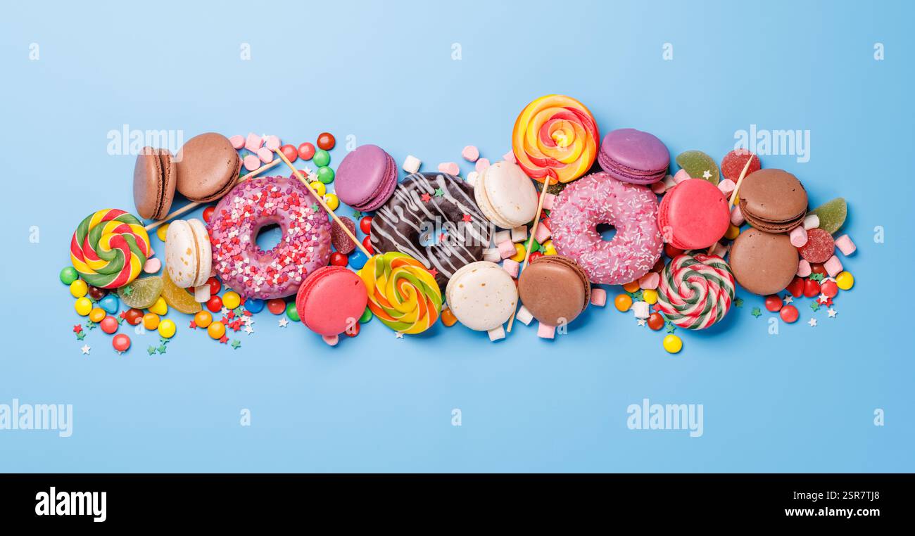 An assortment of colorful sweets, including donuts, macarons, and candies, arranged on a vibrant ...
