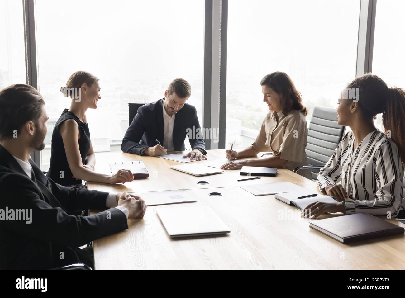 Group of diverse business partners, stakeholders signing contracts Stock Photo