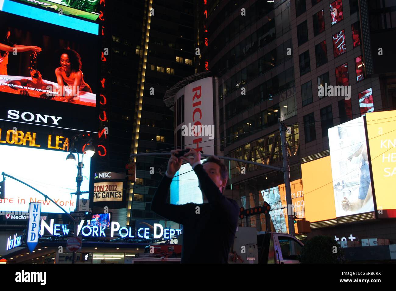 A dazzling display of neon lights and towering billboards bathes New York, Manhattan in a vibrant glow.  Advertising bombards the senses, a constant s Stock Photo