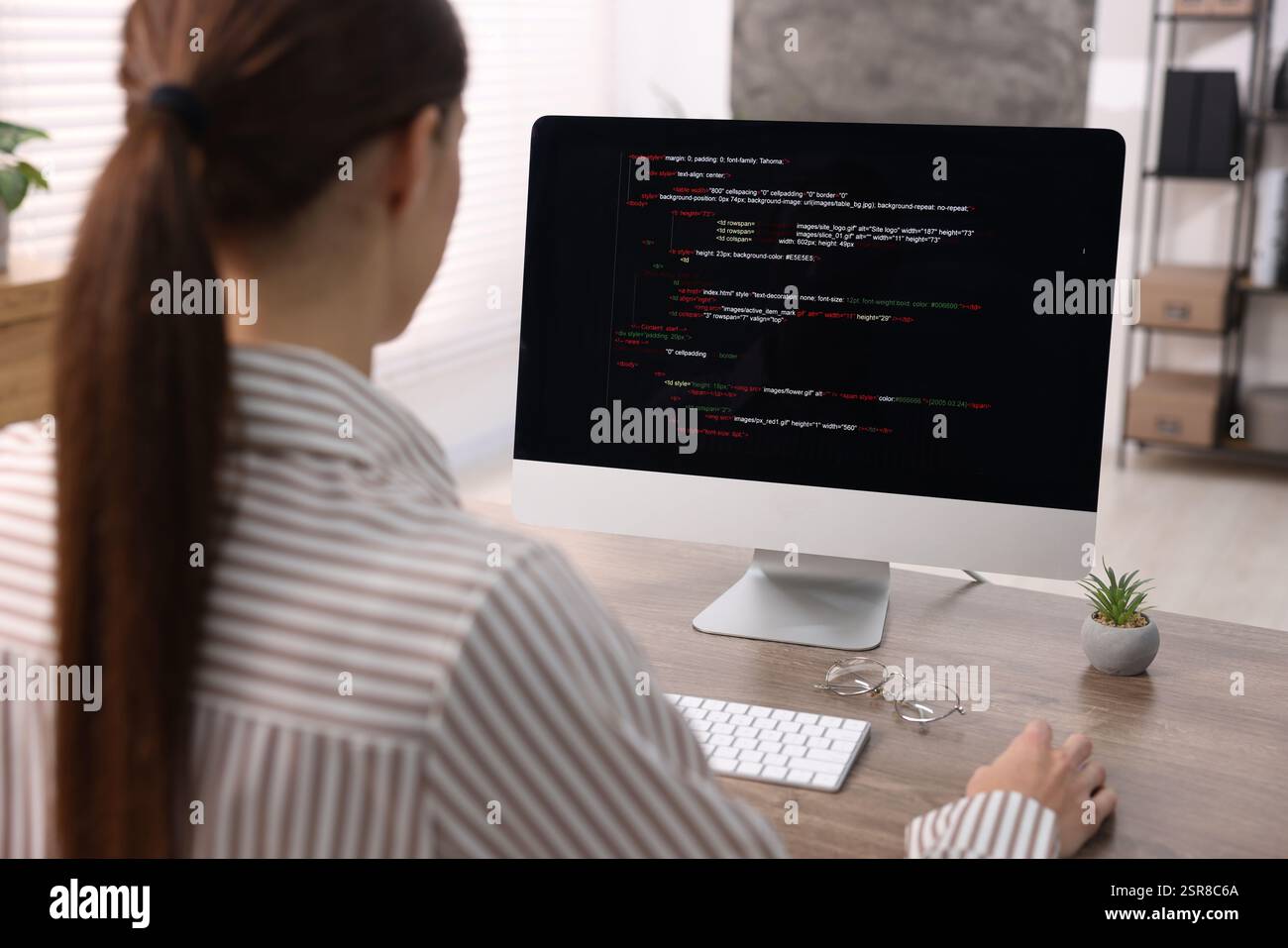 Programmer working on computer at wooden desk indoors, back view Stock ...