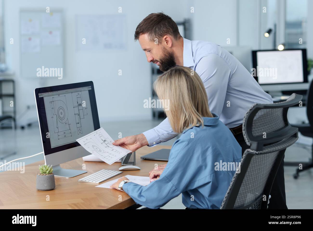 Technicians making digital engineering drawing on computer at desk in office Stock Photo