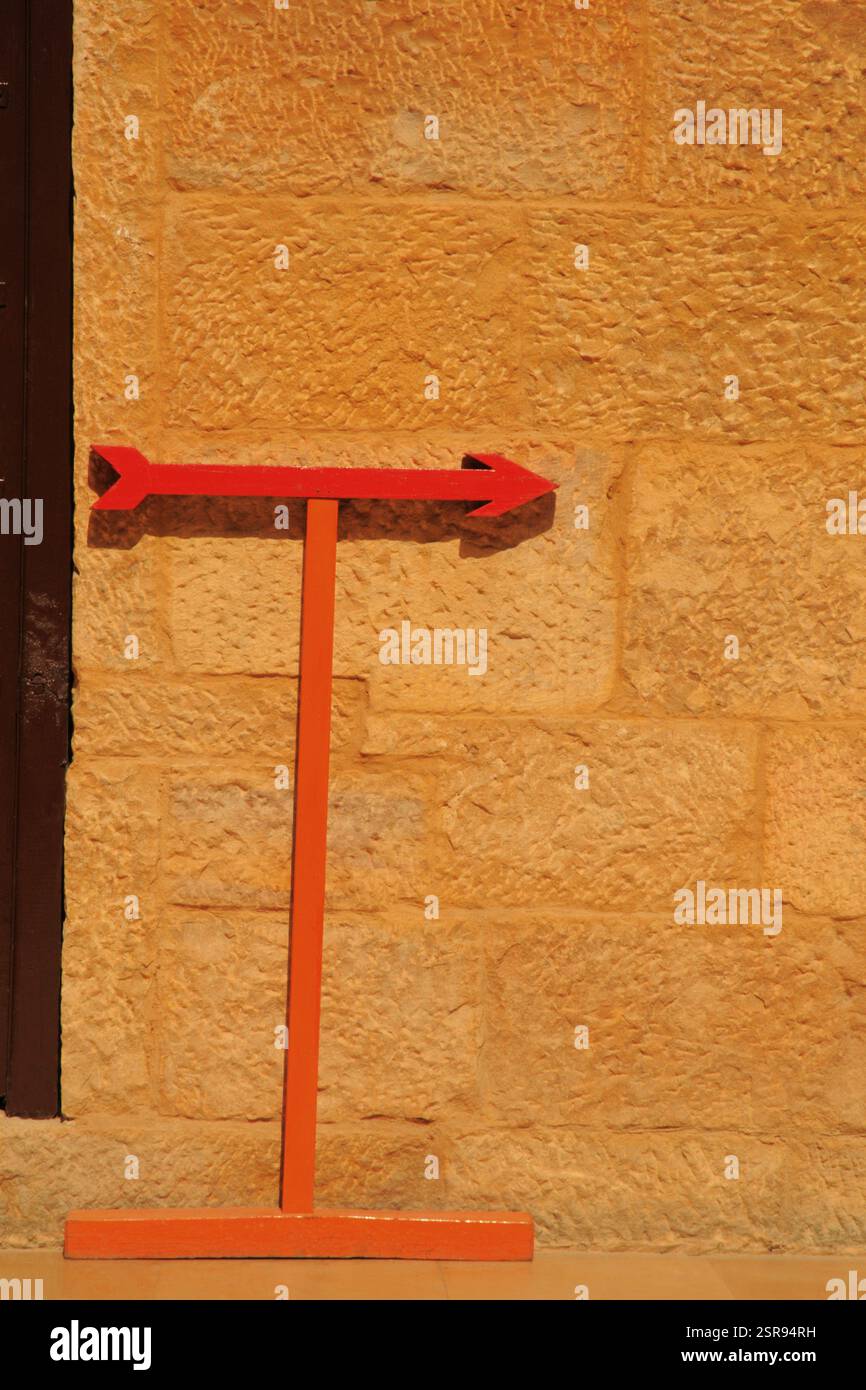Abstract form of red wooden arrow showing direction against sandstone wall in Rajmahal palace in Jaisalmer, Rajasthan, India, Asia Stock Photo