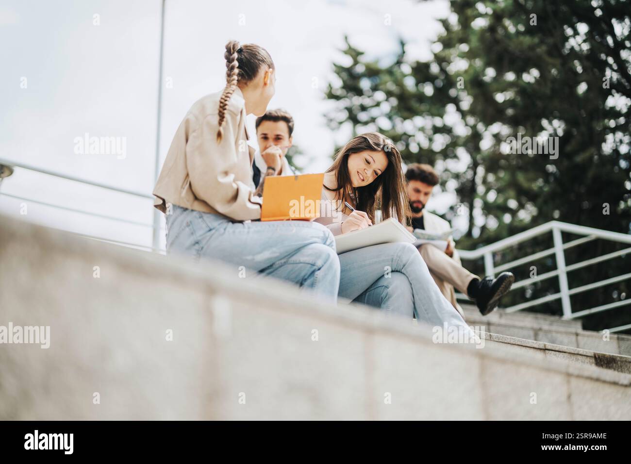 Students collaborating on outdoor steps with professor guidance Stock Photo