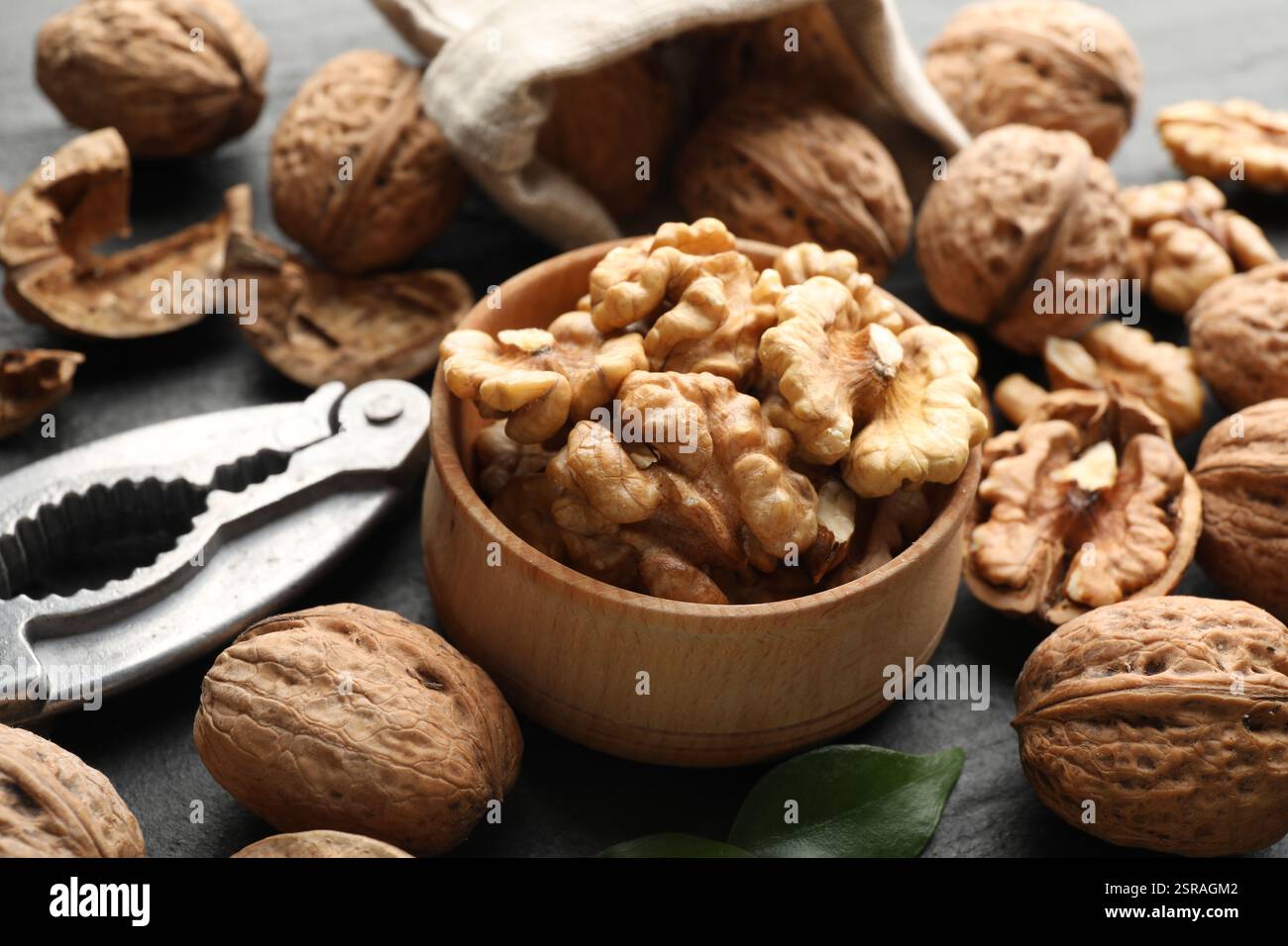 Fresh ripe walnuts, shells and nutcracker on table, closeup Stock Photo