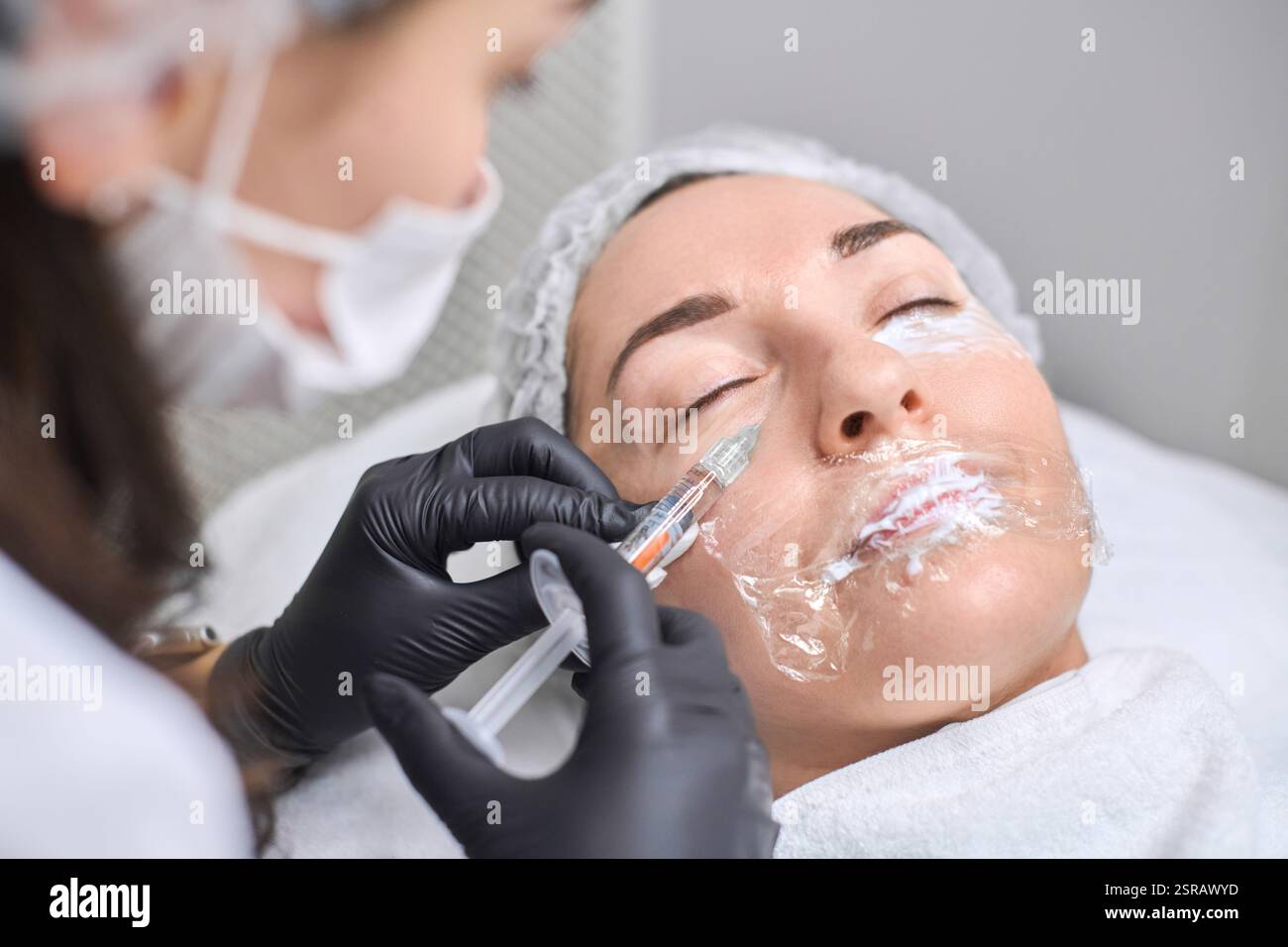 Young woman receives facial injection from professional wearing gloves ...
