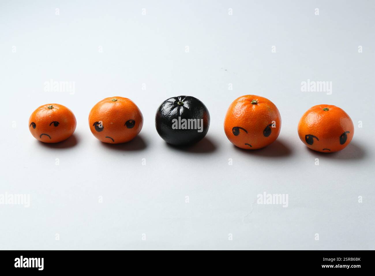 Stop racism. One black tangerine among orange ones on light background Stock Photo