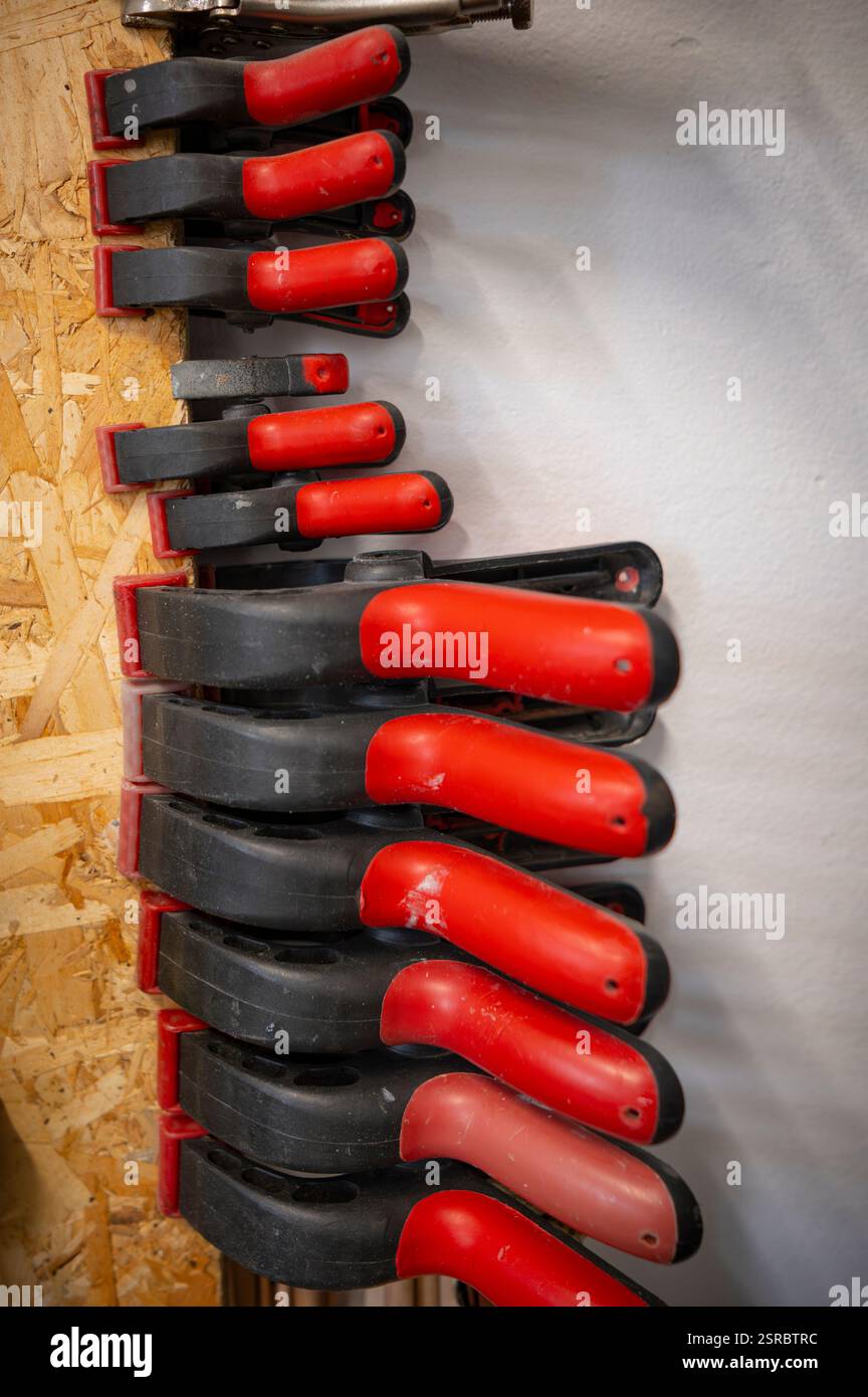 Black plastic clamps with red handles attached to a panel, scene from an art-studio. Stock Photo