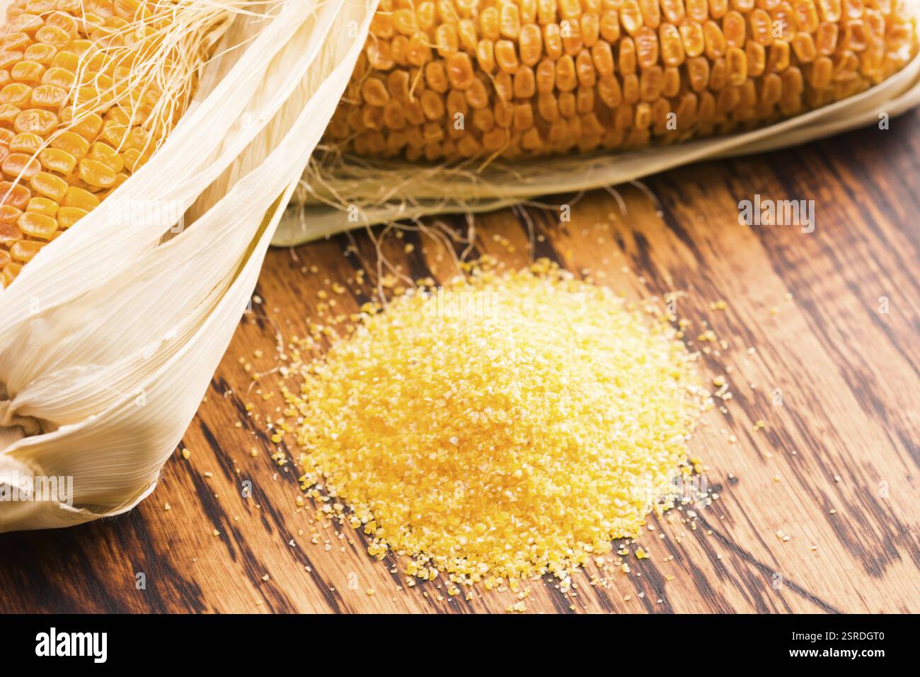Corn groats and seeds, corncobs on wooden rustic table Stock Photo