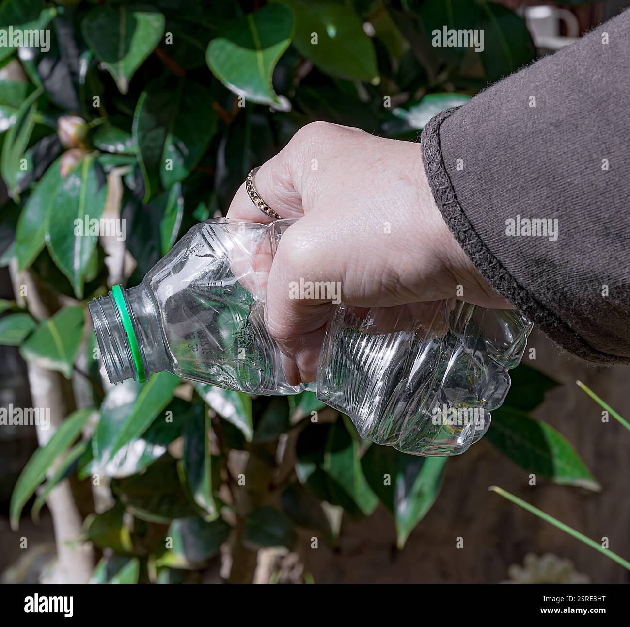 Empty and crumpled plastic bottle with one hand. Stock Photo