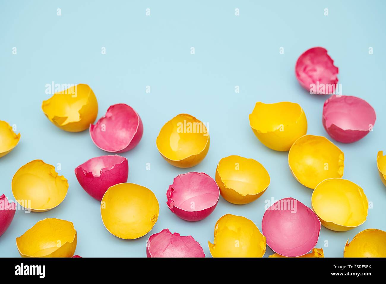 Cracked Yellow and Pink Easter Eggshells on Blue. Flat Lay with Copy Space. Stock Photo