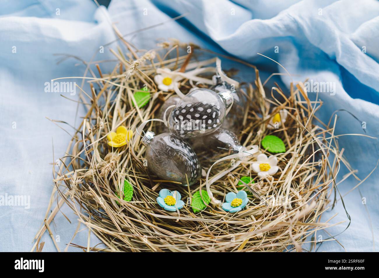 Colorful Easter eggs nestled in a nest surrounded by flowers and straw ...