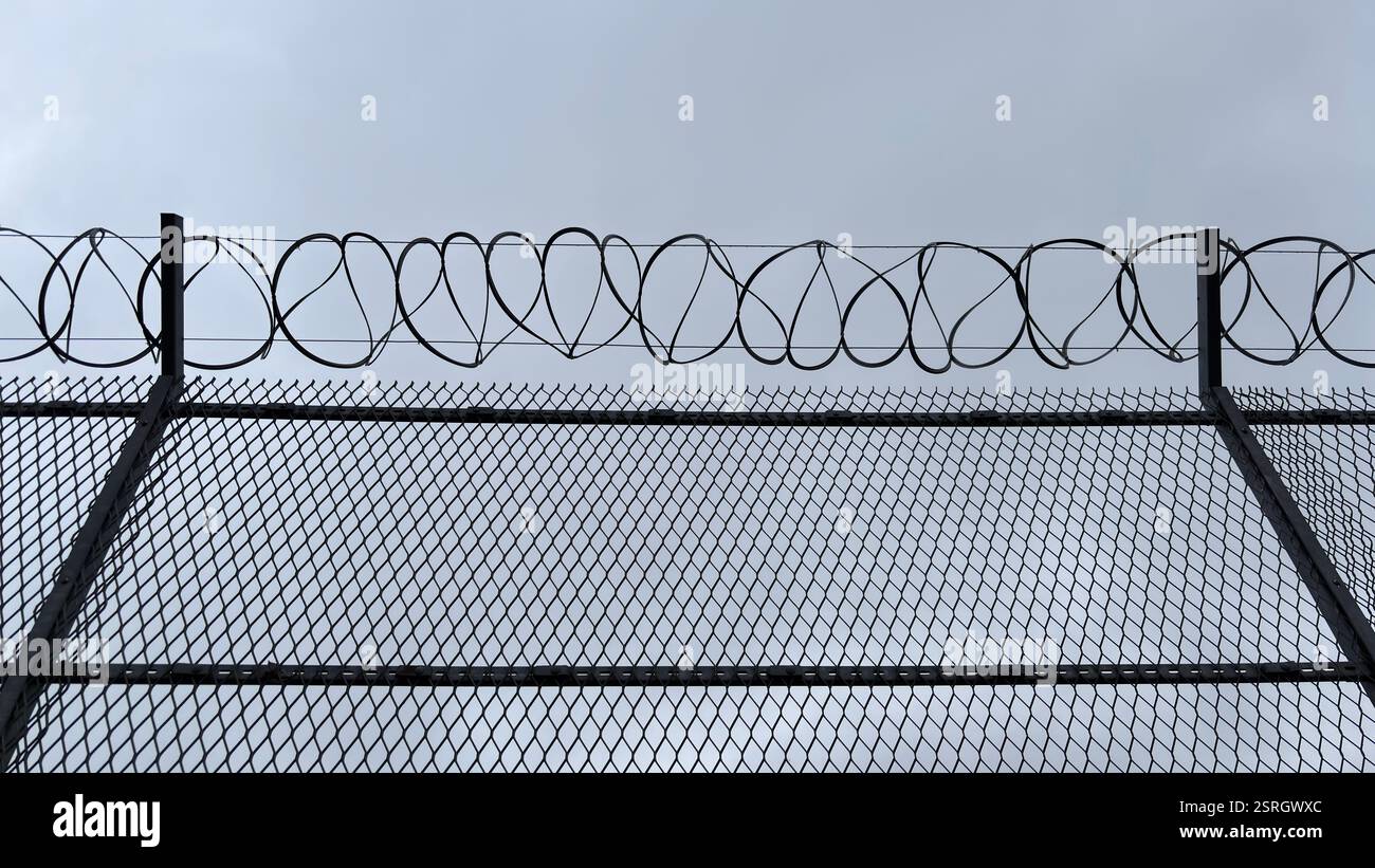 Brutal razor wire topped fence. Urban security fencing. - Smartphone Captured Stock Image