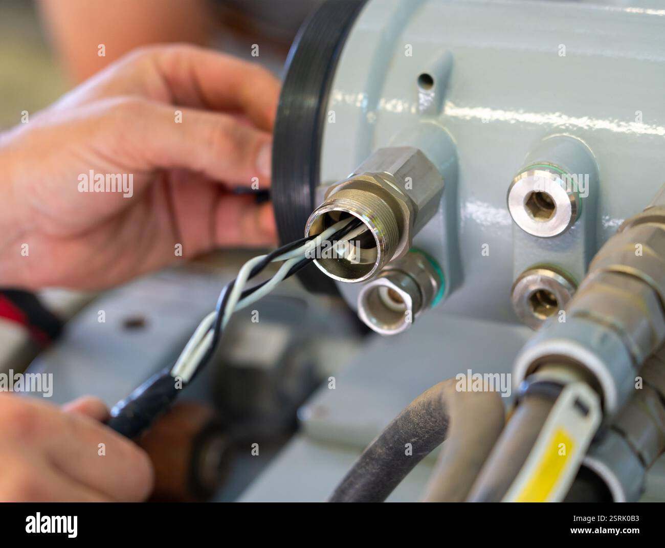 Hands connecting industrial wires to equipment during maintenance ...