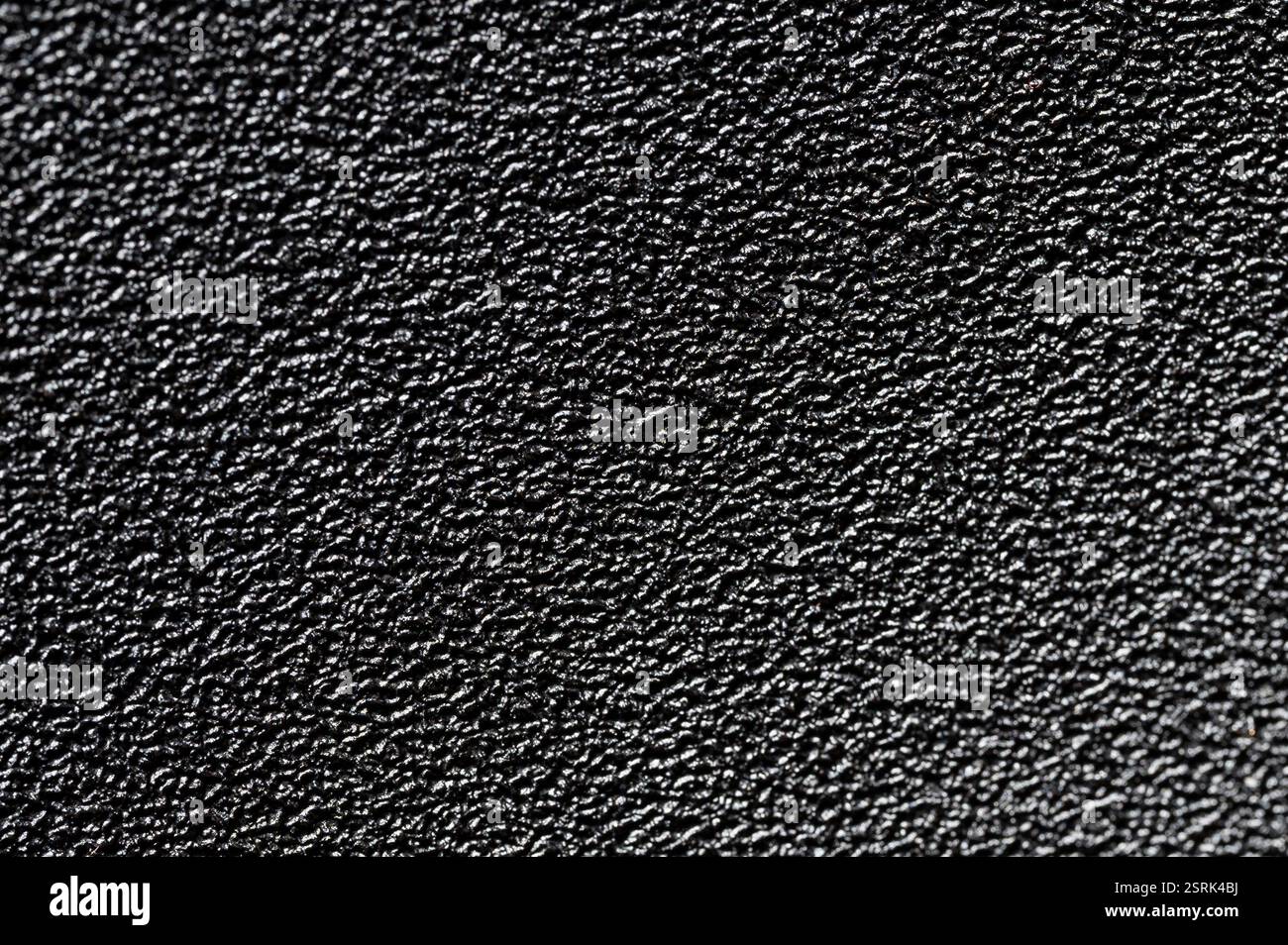 Black grainy plastic surface background with bump close up view Stock Photo