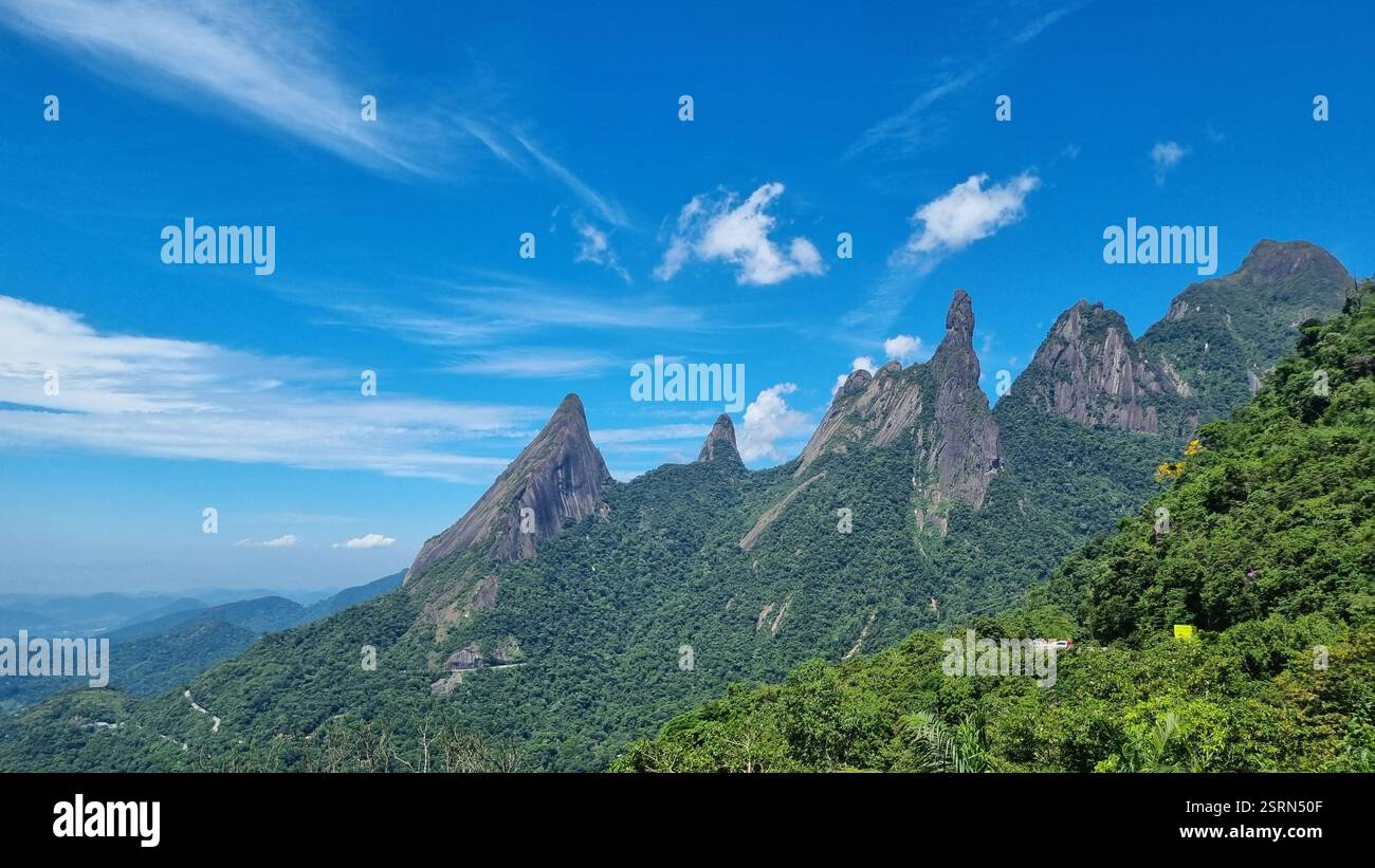 This spectacular mountain landscape features towering, jagged peaks piercing the sky, enveloped in lush green forest. - Smartphone Captured Stock Image