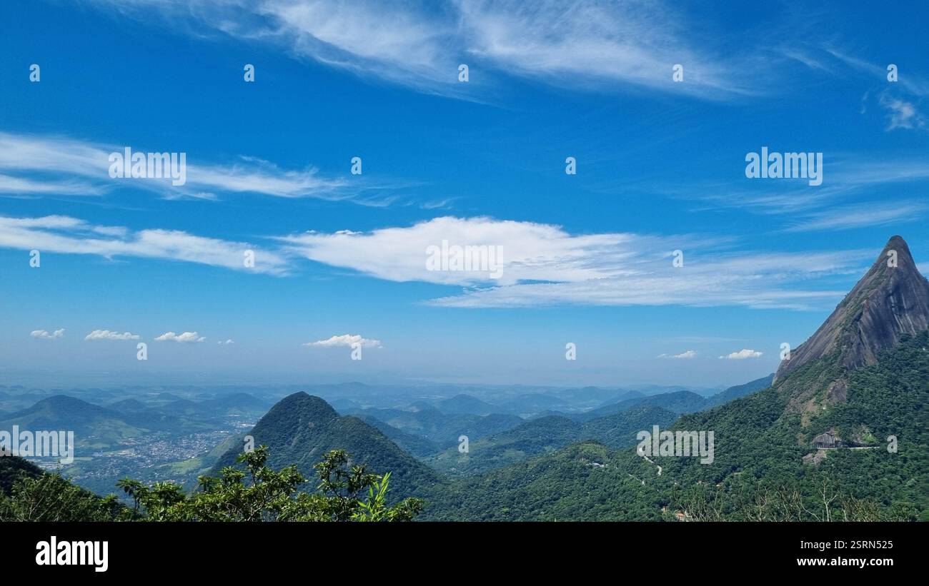 This spectacular mountain landscape features towering, jagged peaks piercing the sky, enveloped in lush green forest. - Smartphone Captured Stock Image