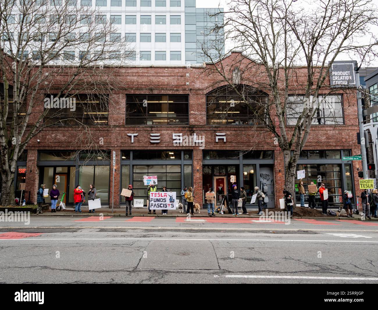 Protesters rally outside the Tesla showroom in downtown Seattle, holding signs and chanting in protest against Elon Musk’s business practices. Stock Photo
