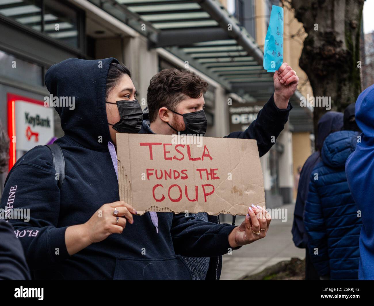 Protesters rally outside the Tesla showroom in downtown Seattle, holding signs and chanting in protest against Elon Musk’s business practices. Stock Photo