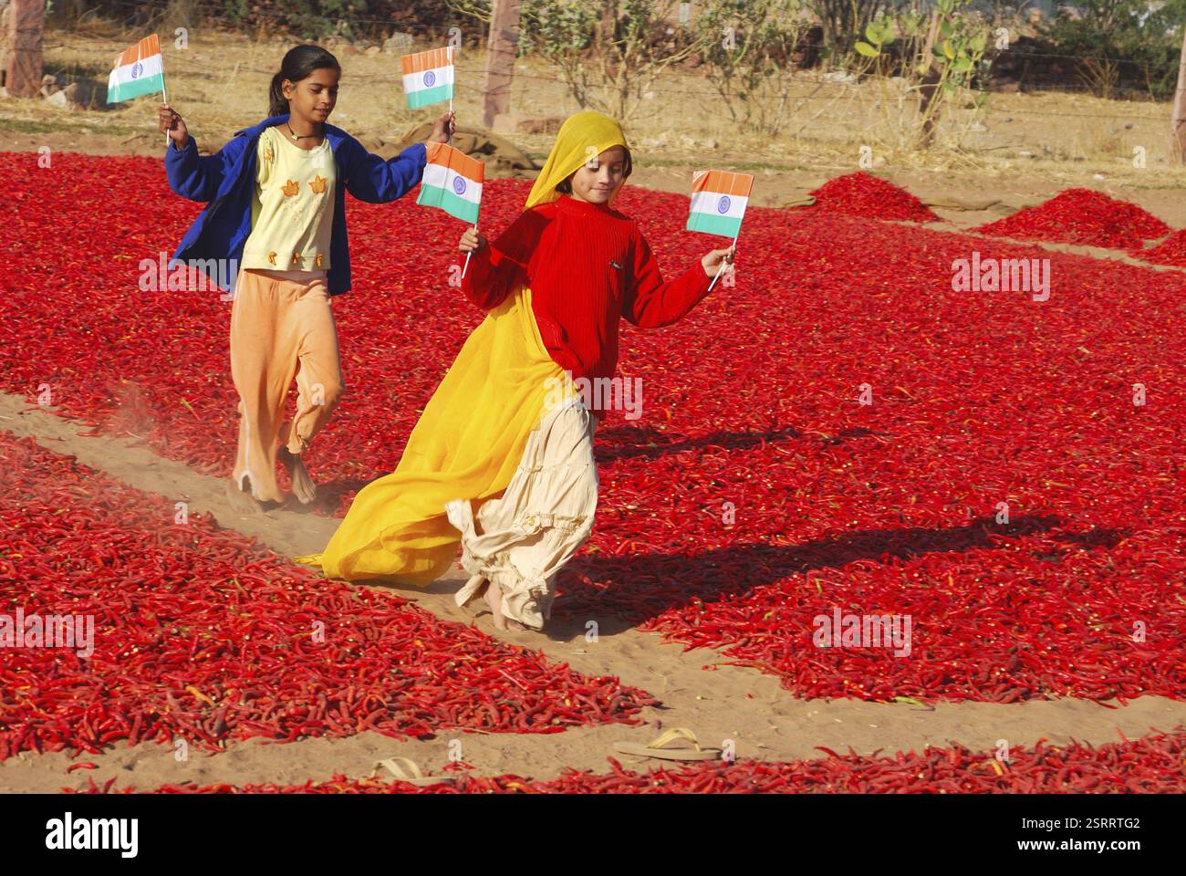 Girls running across red chilli pepper with national flags in hands ...
