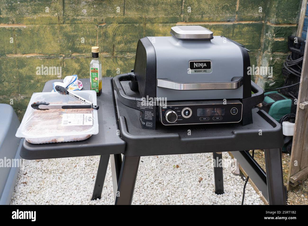 Electric powered outdoor oven by Ninja Woodfire cooking chicken, UK. Concept: outdoor cooking, no charcoal, no gas, electricity powered Stock Photo