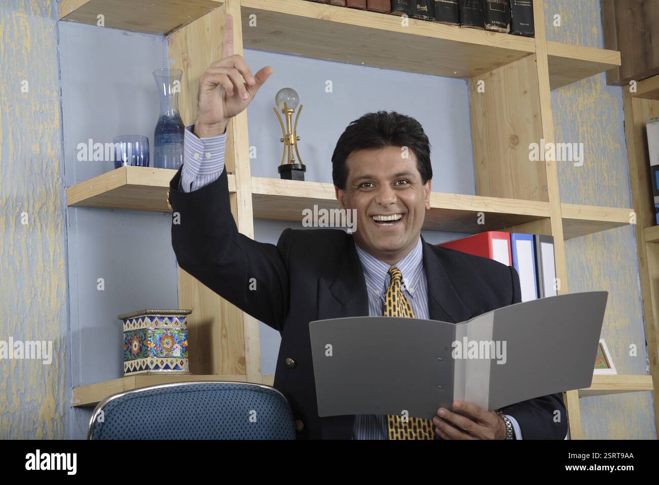 Executive holding file in one hand and raising right hand indicating ...