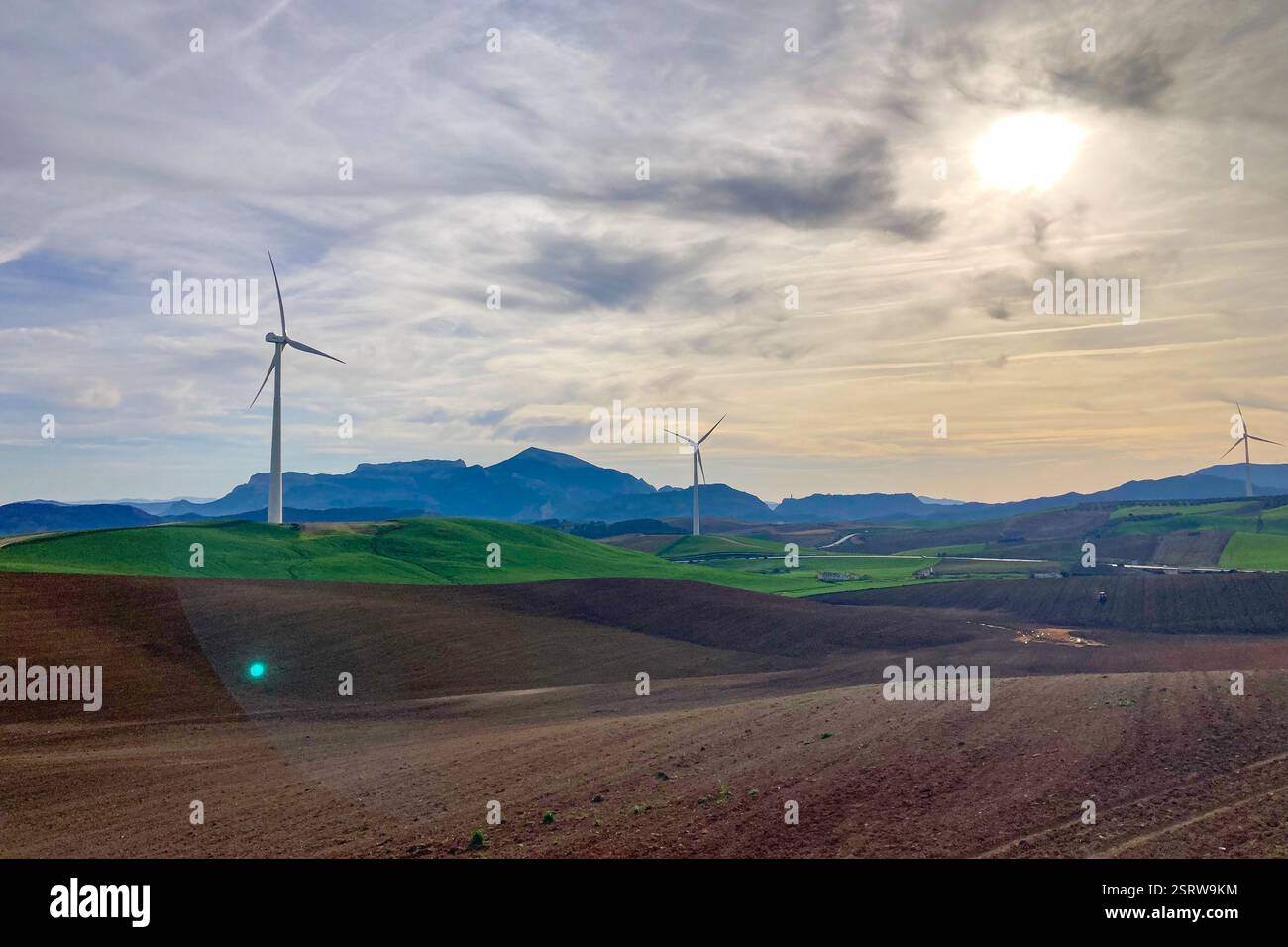 A windmill standing in a field of barley, its blades turning slowly in the wind, Andalusia, Spain - Smartphone Captured Stock Image