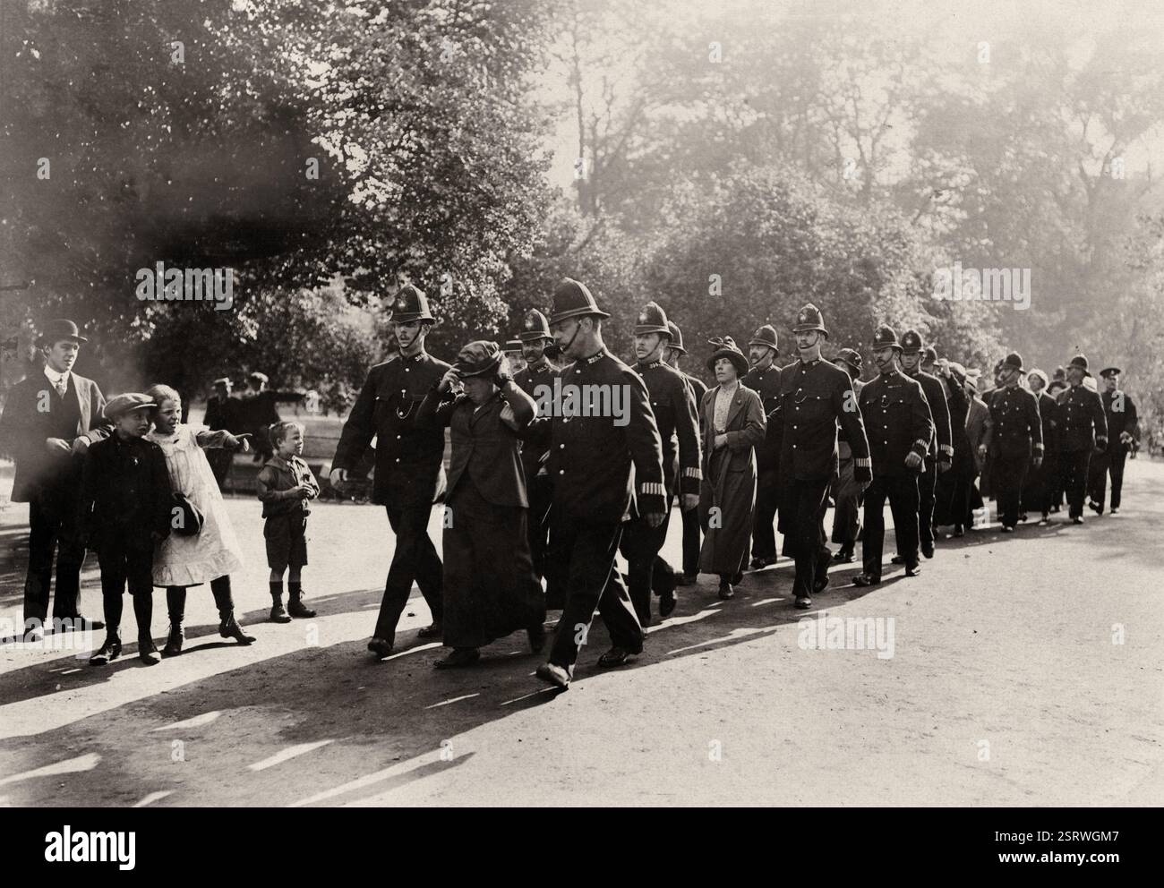Flora Drummond and others under arrest, 1914, London, England.  a procession of women, each escorted by two policemen, walking through a park. Archive women's vote photograph Stock Photo