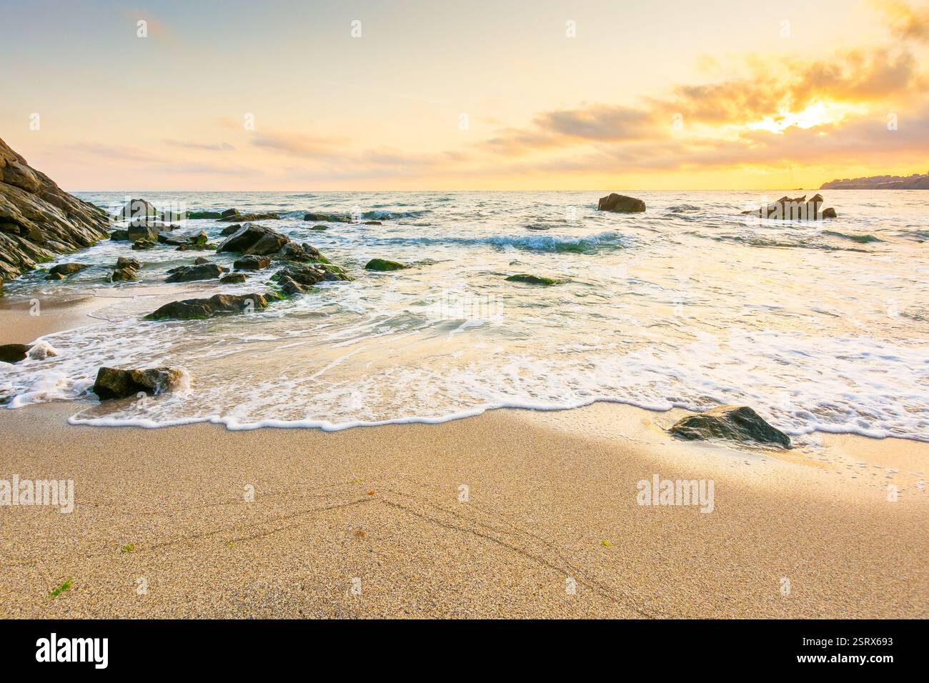 summer holiday season at the seaside. beautiful seascape at sunrise. golden sandy beach in morning light. sun behind fluffy clouds on sky above horizo Stock Photo