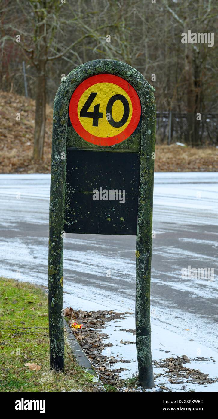 A bright circular speed limit sign indicates 40 km/h, covered in moss ...