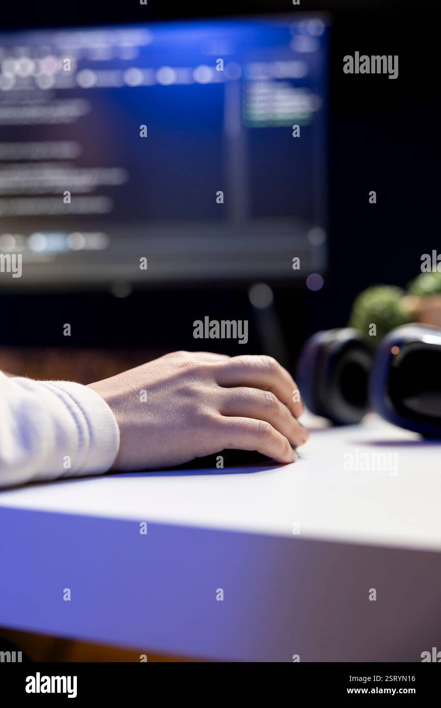 Teleworking IT admin working from RGB lit home, testing and deploying programs and systems. Close up of software technician checking code displayed on computer screens in apartment Stock Photo