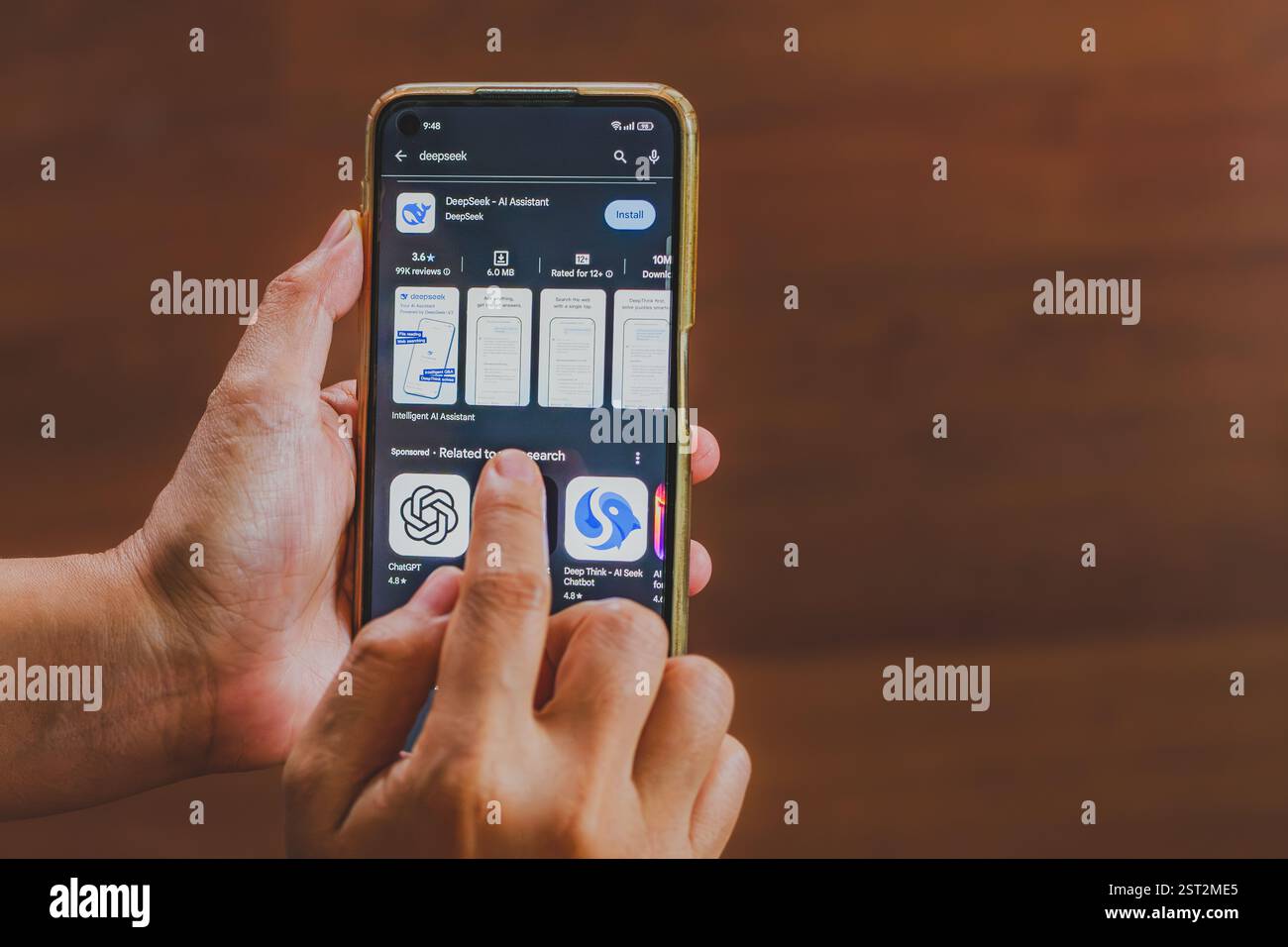 Balikpapan, Indonesia - Feb 16th 2025. a person's hands holding a mobile phone. The screen displays the app listing for DeepSeek AI Assistant. Stock Photo