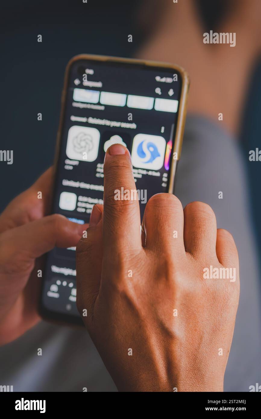 The person's finger is touching the screen, seemingly selecting an AI app. Stock Photo