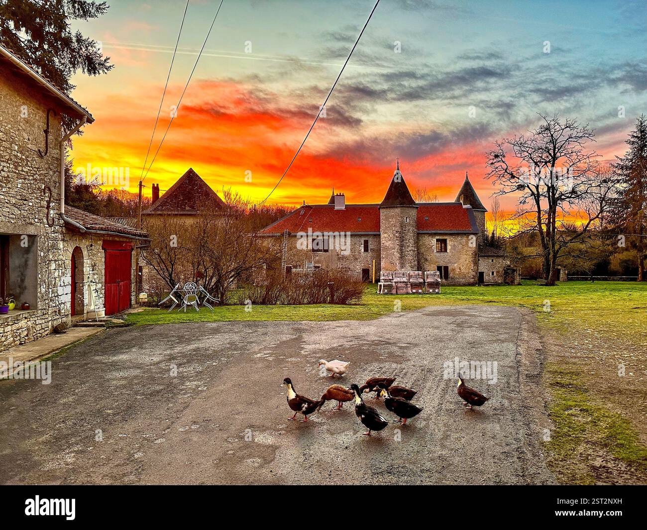 Fiery sunset over an old castle A majestic sunset overlooking an old castle and some ducks in the courtyard. - Smartphone Captured Stock Image