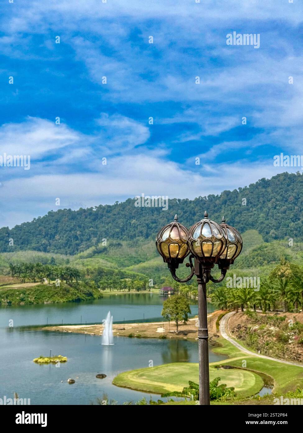 Vintage street lamp with a lake and green Golf hills view3 A vintage-style street lamp stands in front of a serene landscape featuring a peaceful lake - Smartphone Captured Stock Image
