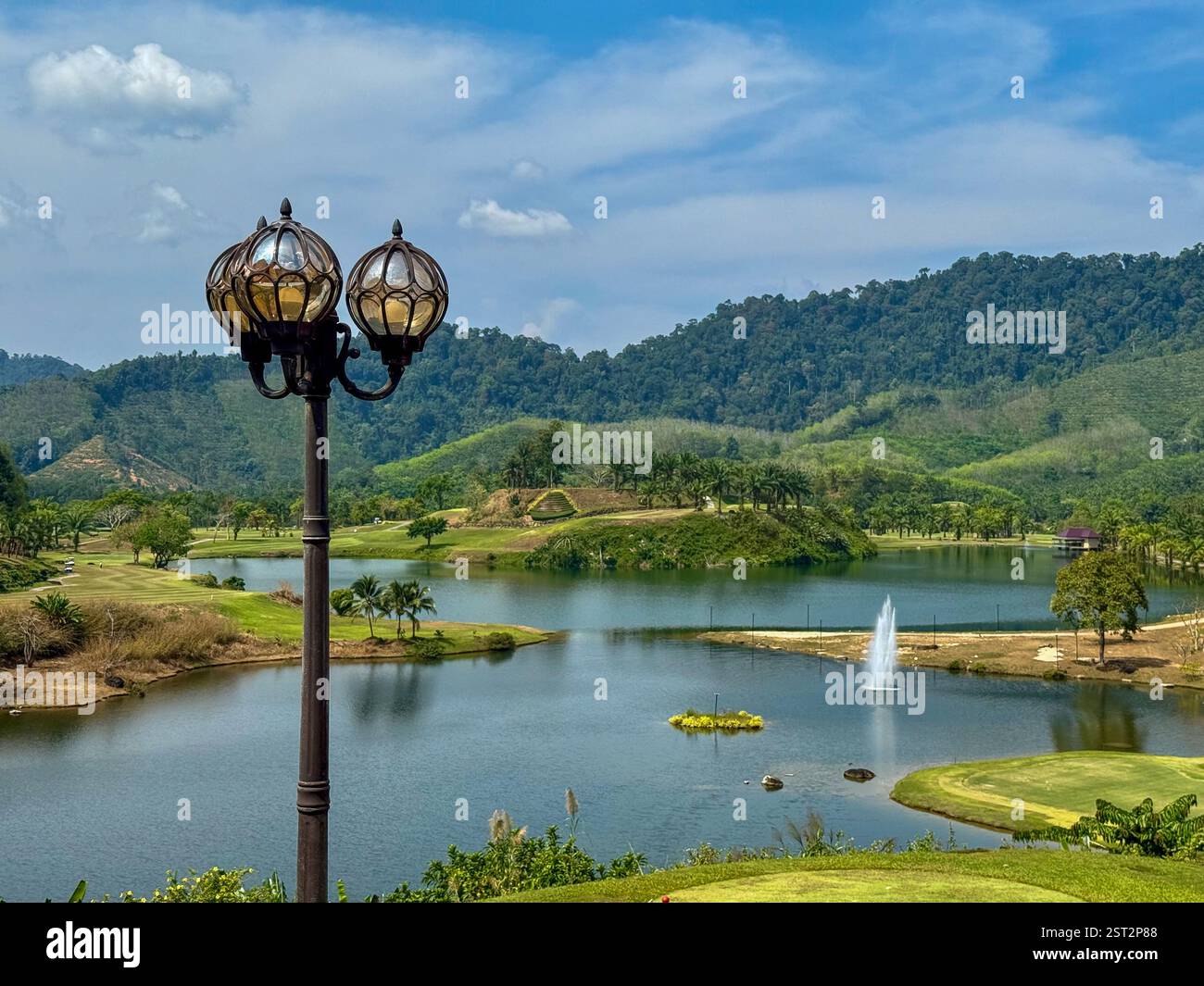 Vintage street lamp with a lake and green hills view A vintage-style street lamp stands in front of a serene landscape featuring a peaceful lake - Smartphone Captured Stock Image