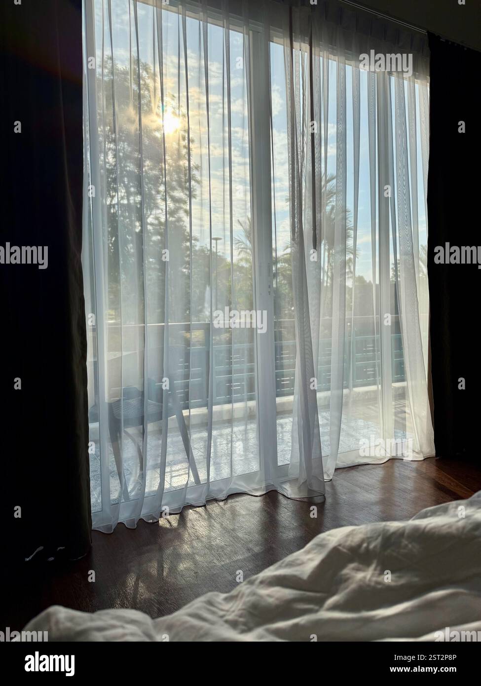 Peaceful Morning Behind a Sheer Curtain A serene morning view from bed, looking through a large glass door veiled by delicate sheer white curtains. So - Smartphone Captured Stock Image