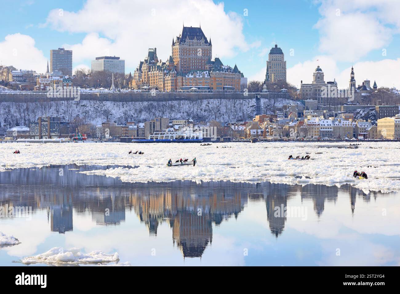 Traditional Ice Canoe Race from Quebec to Levis during winter Carnival with city skyline reflected on the frozen Saint Lawrence River Stock Photo