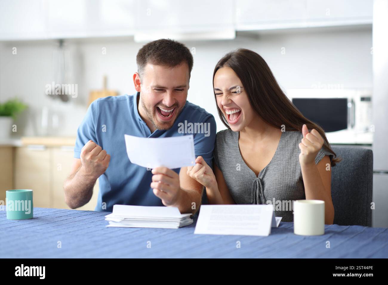 Excited couple checking bill in the kitchen at home Stock Photo - Alamy