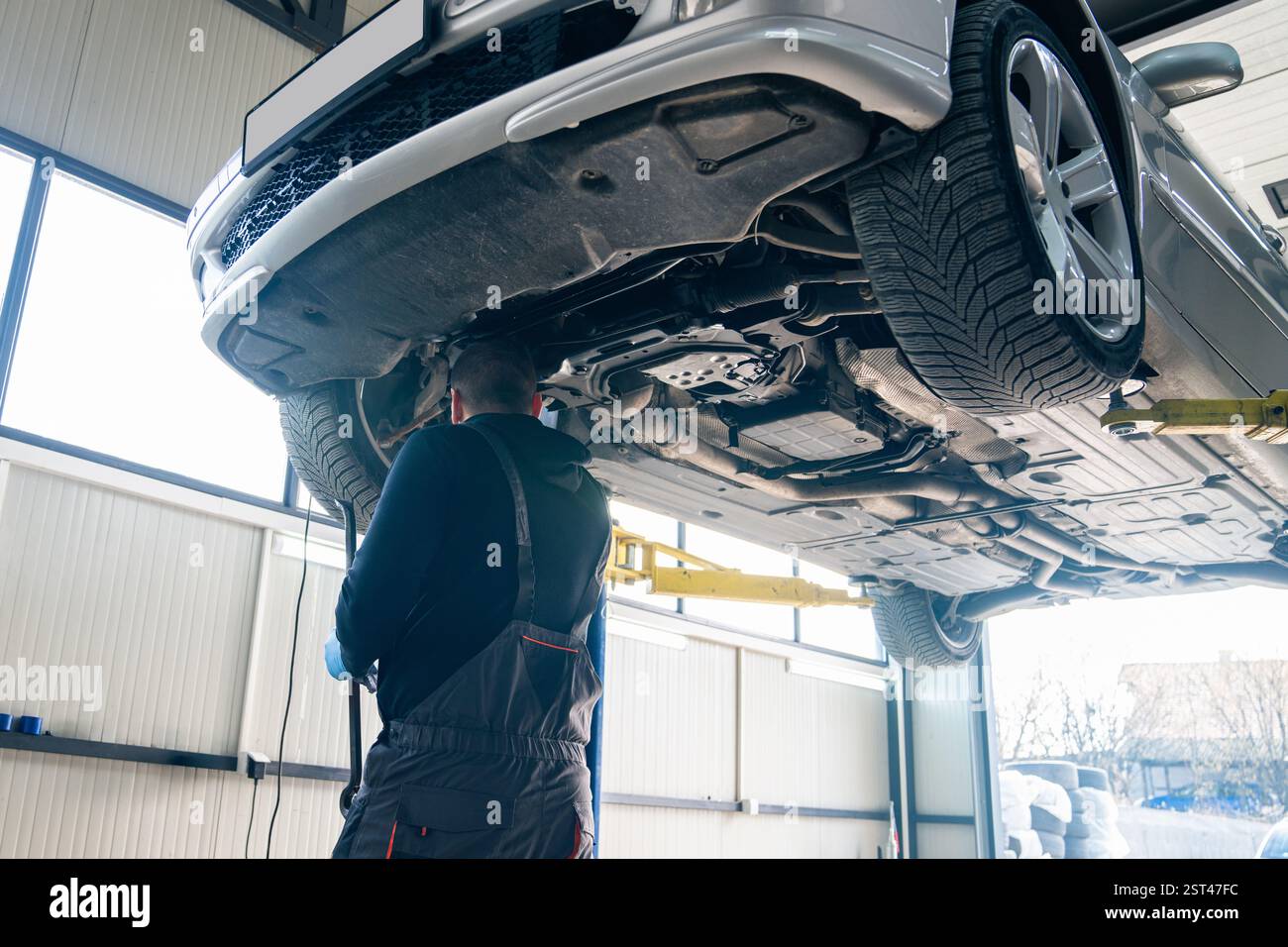 Serviceman checks car suspension on a column lift in car service Stock ...