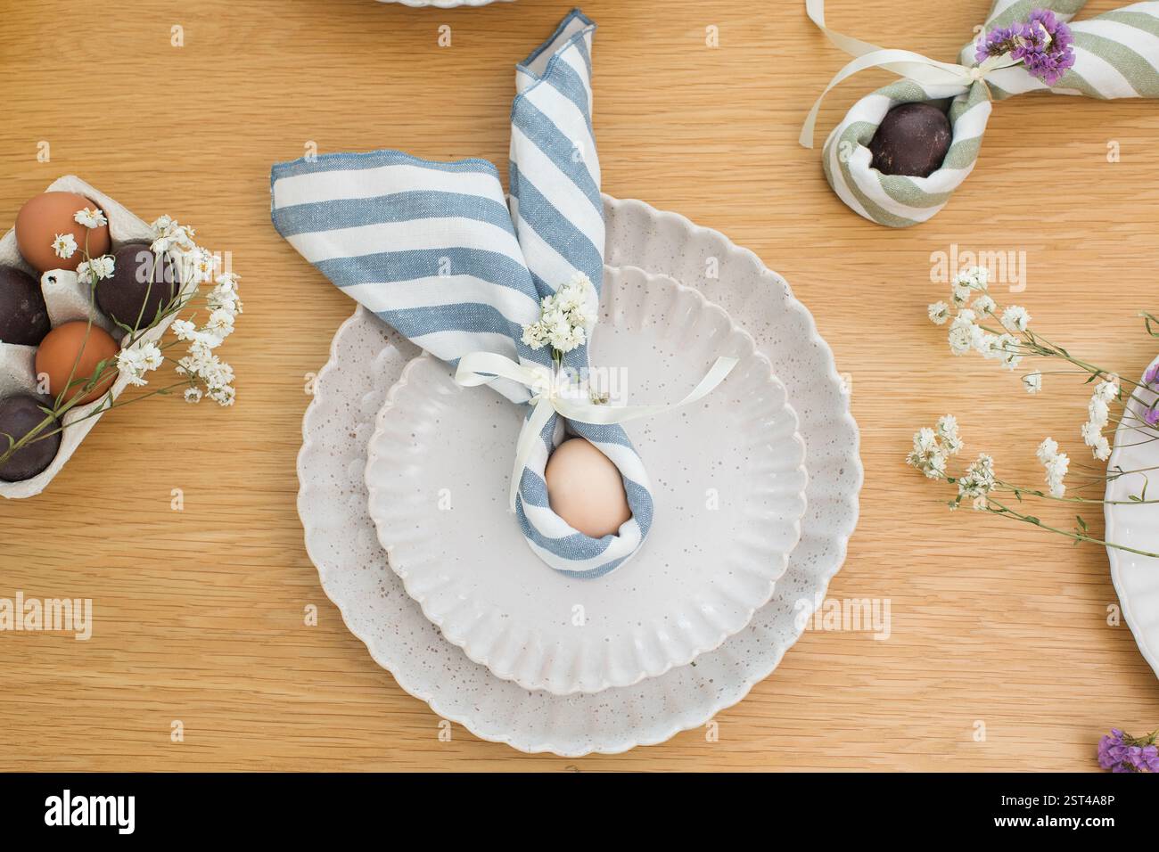 Easter egg wrapped in linen napkin in the shape of bunny with ears. Happy Easter Stock Photo