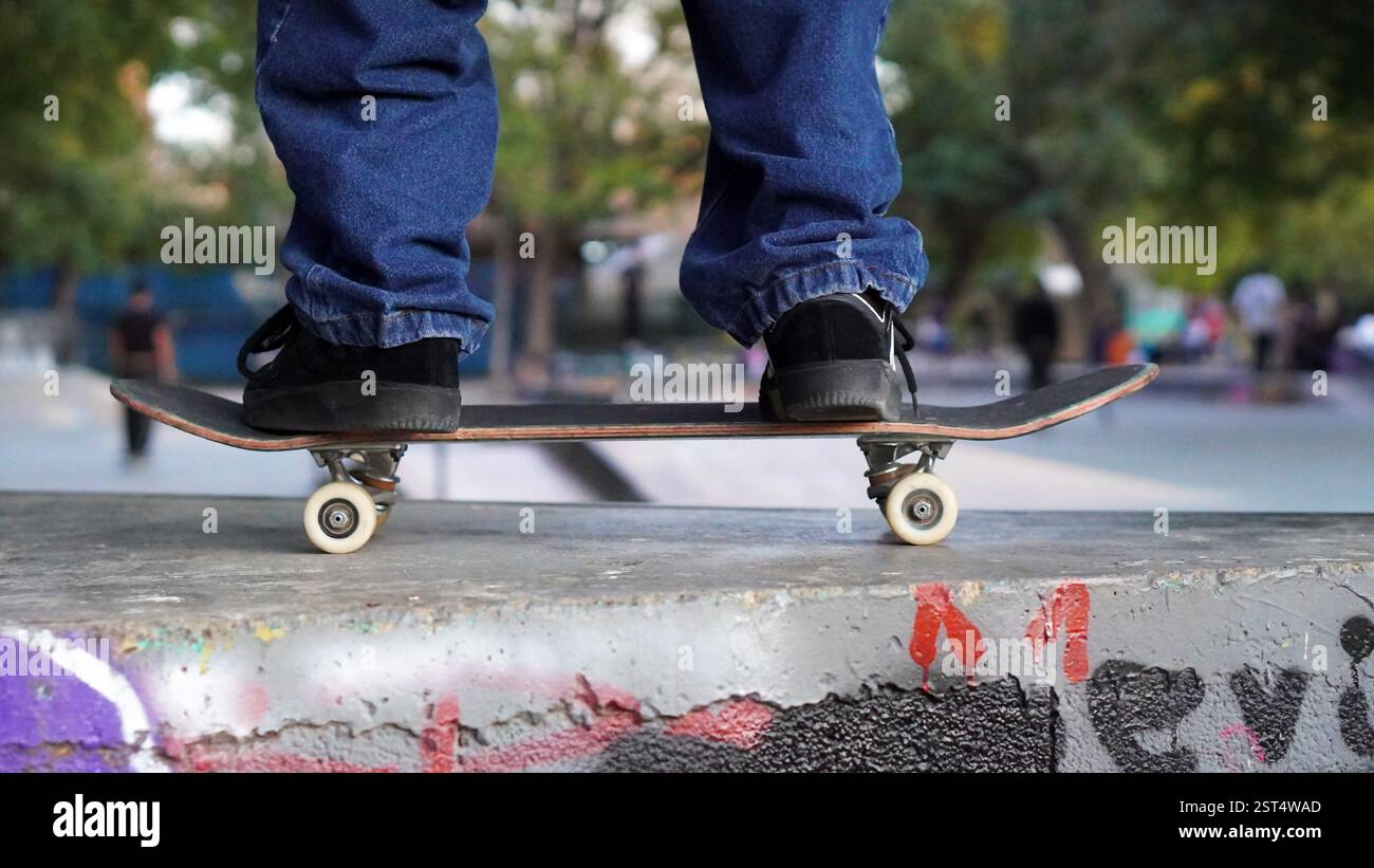 skater's feet and skateboard practicing in a skate park with other ...