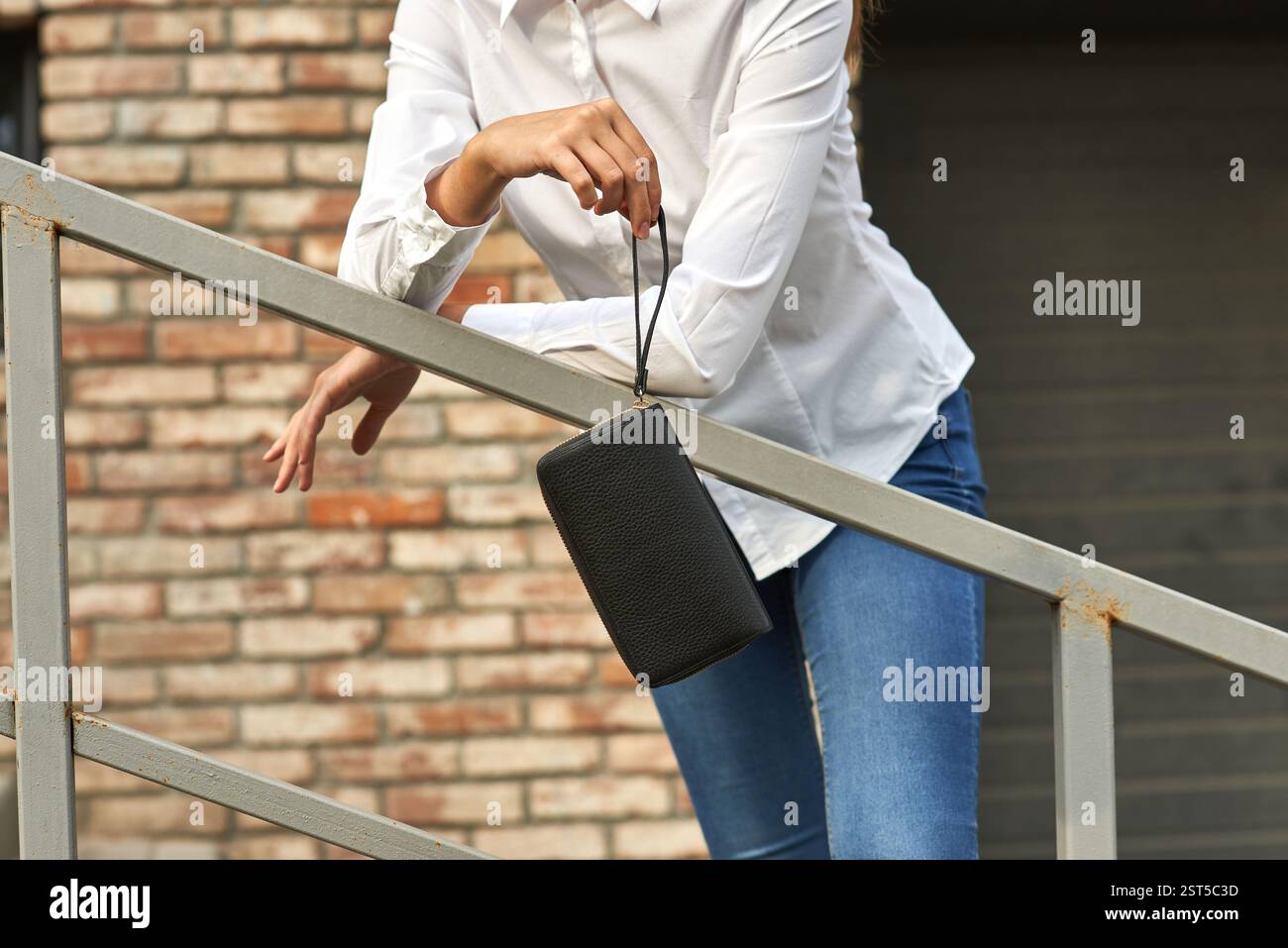 Resting On Railing Casual attire woman, resting on railing while holding black handbag, in ...