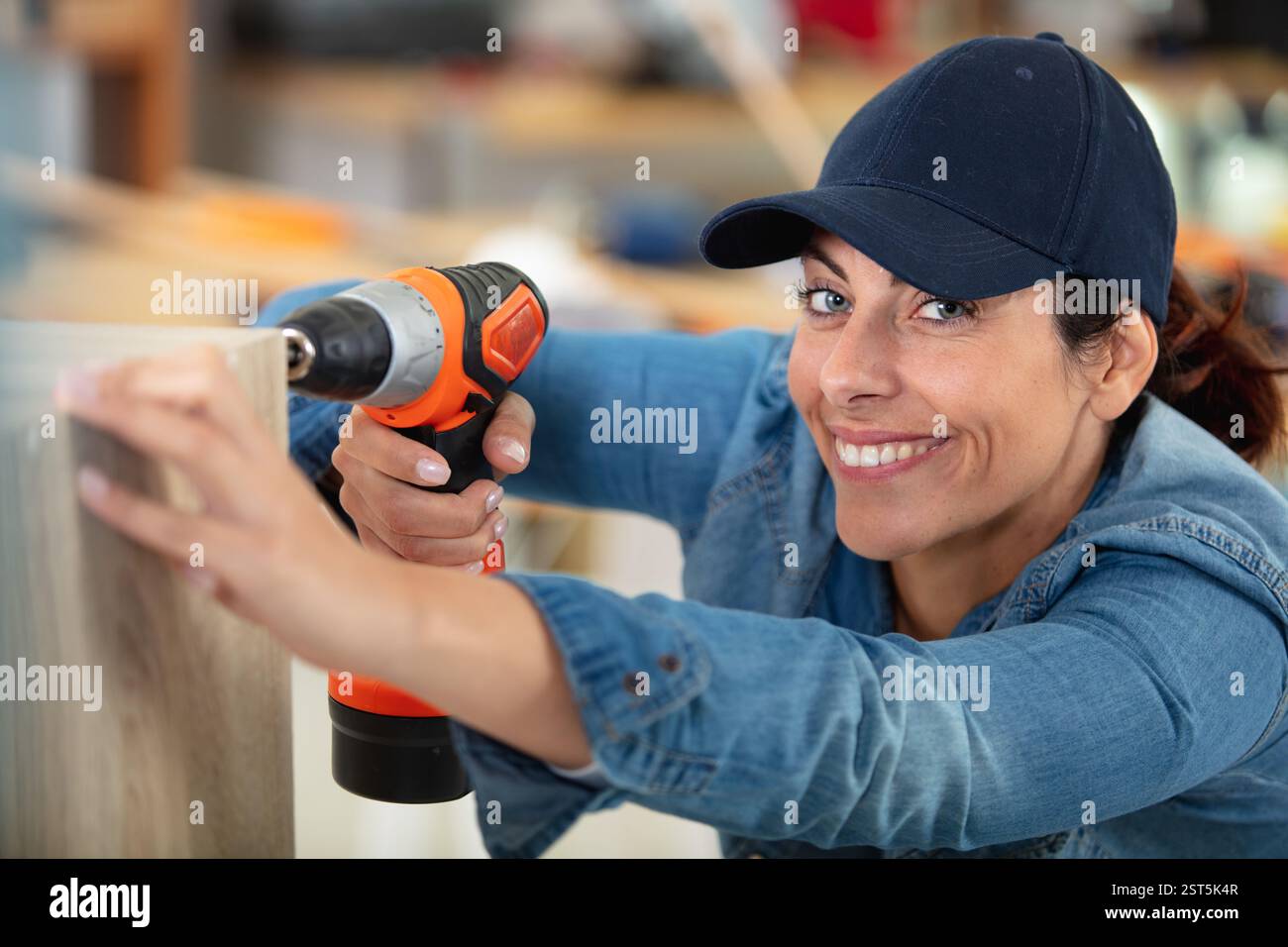 cheerful woman using a cordless screwdriver Stock Photo