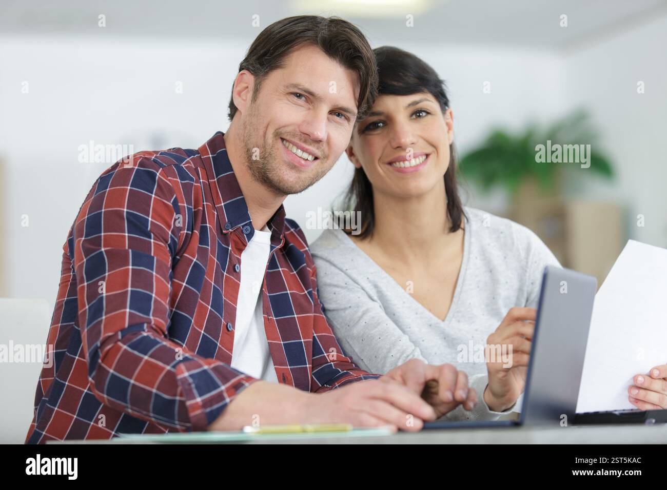 happy couple using laptop and holding paperwork Stock Photo