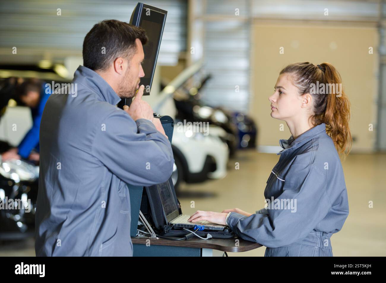 mechanic training female apprentice to use computerised equipment Stock Photo