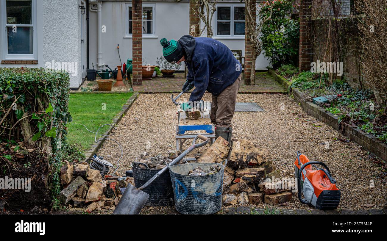 A workman rebuilding a brick and flint wall reusing old bricks. Stock Photo