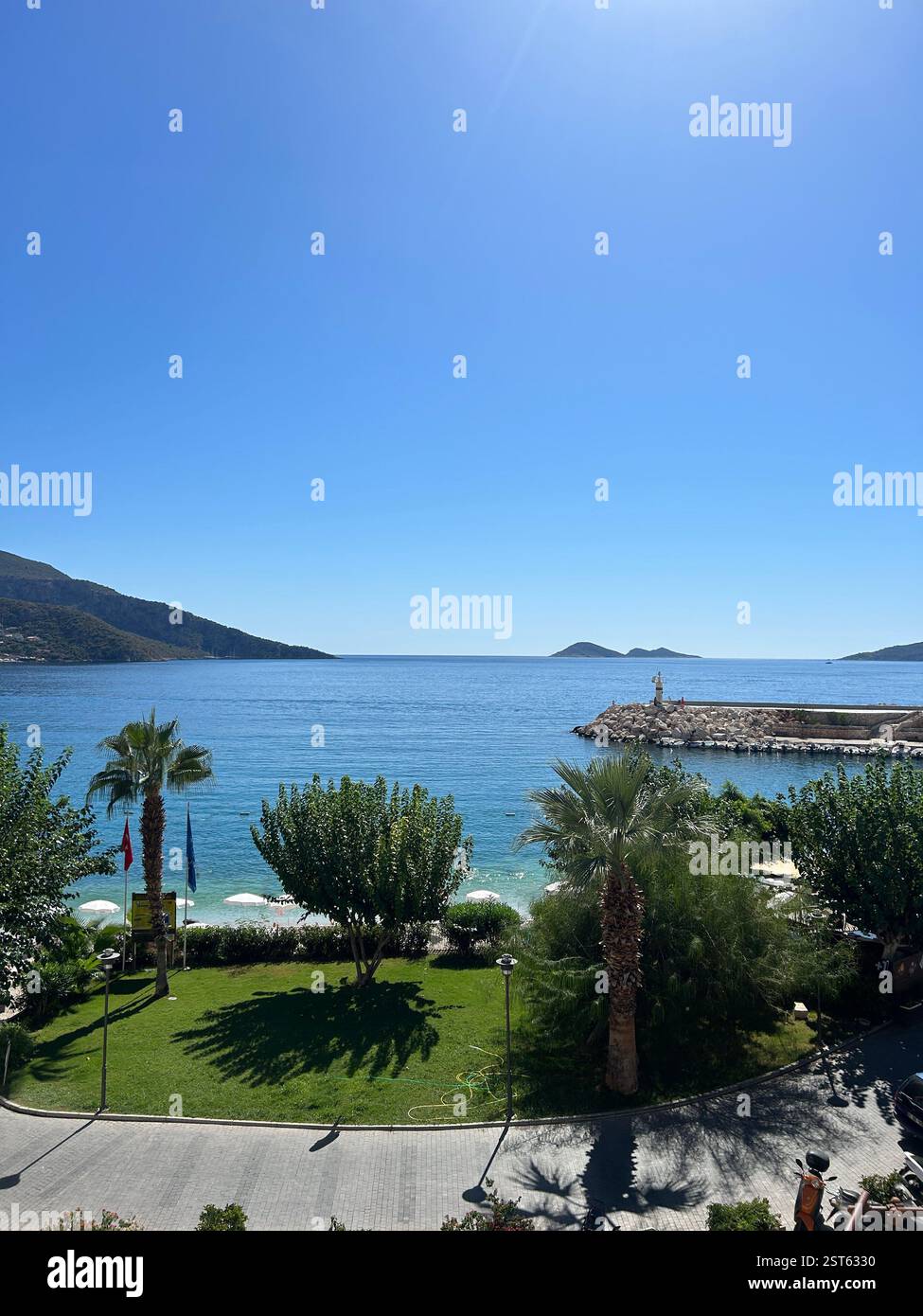 View of the Mediterranean Sea and a beach surrounded by mountains and greenery - Smartphone Captured Stock Image