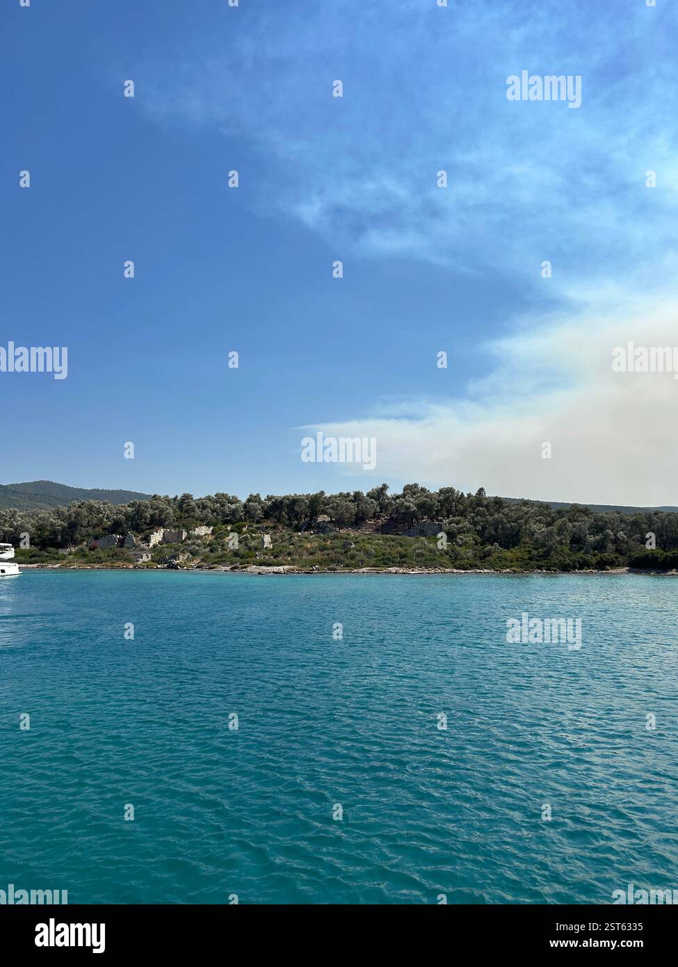The crystal clear blue waters of the Mediterranean Sea against the mountains and trees - Smartphone Captured Stock Image