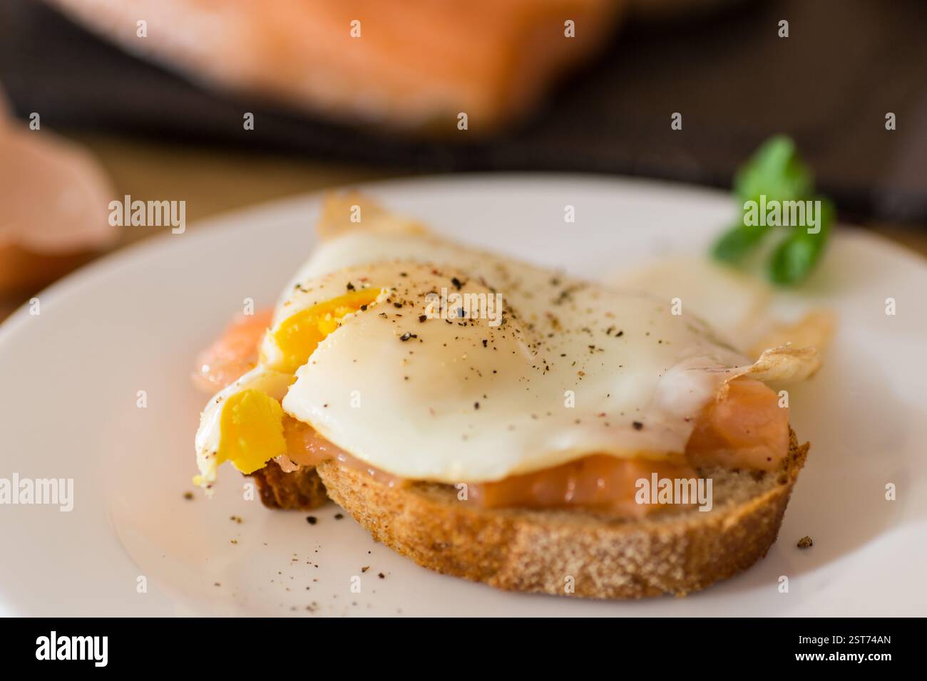 A slice of bread with lightly salted red fish and a cooked egg for breakfast. Stock Photo